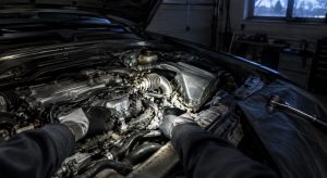 Kädet moottoritilassa otsalampun valossa hämärässä autotallissa